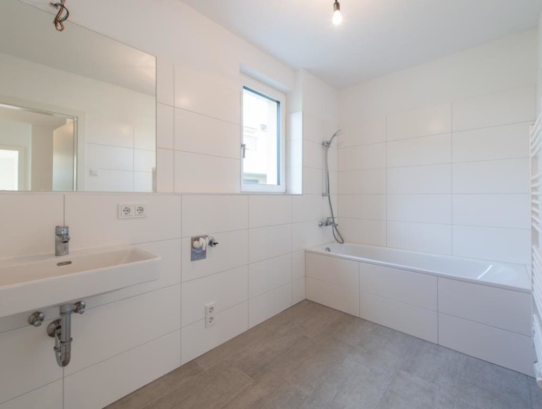 Geräumiges Badezimmer mit Duschwanne, Waschbecken, Handtuchwärmer und Waschmaschinenanschluß