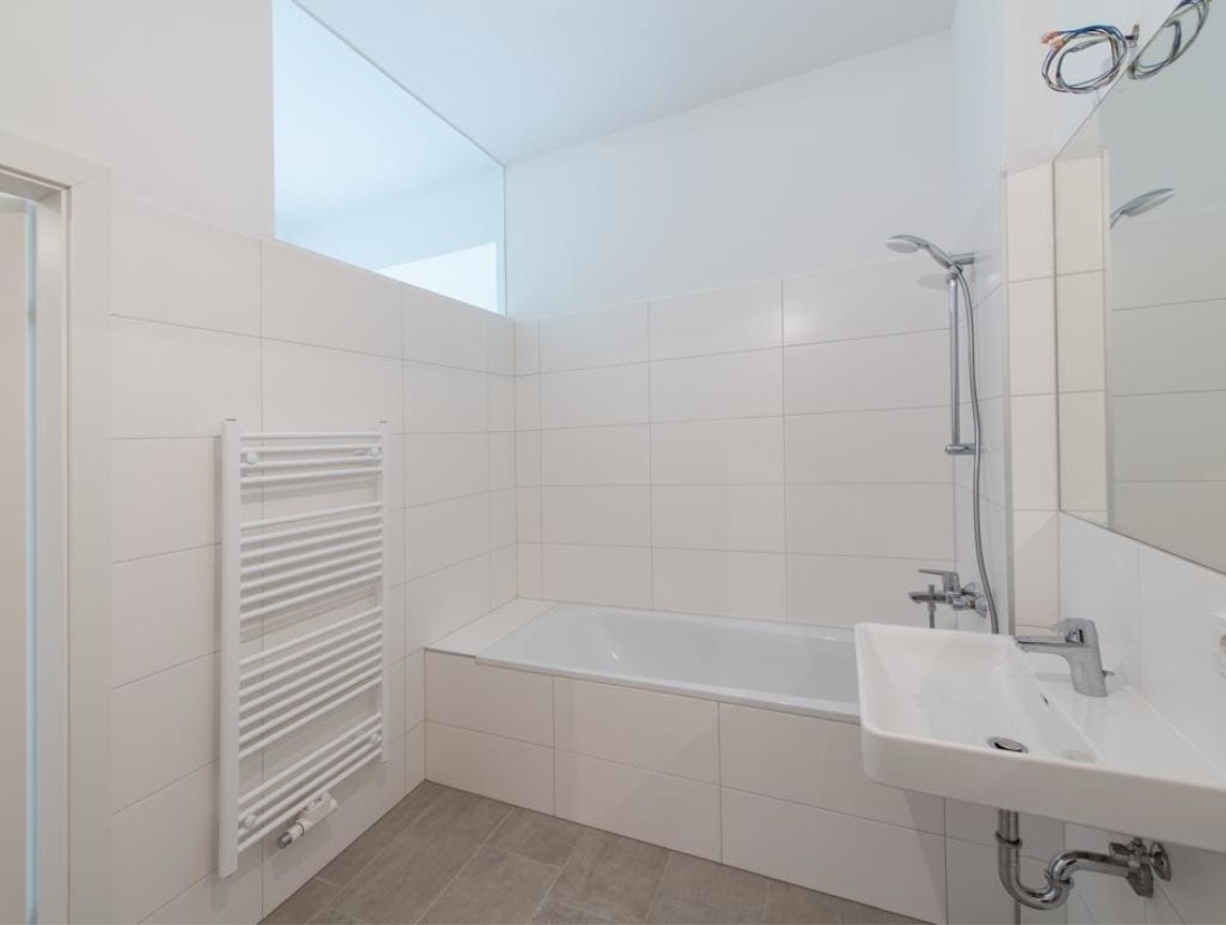 Geräumiges Badezimmer mit Duschwanne, Waschbecken, Handtuchwärmer und Waschmaschinenanschluss