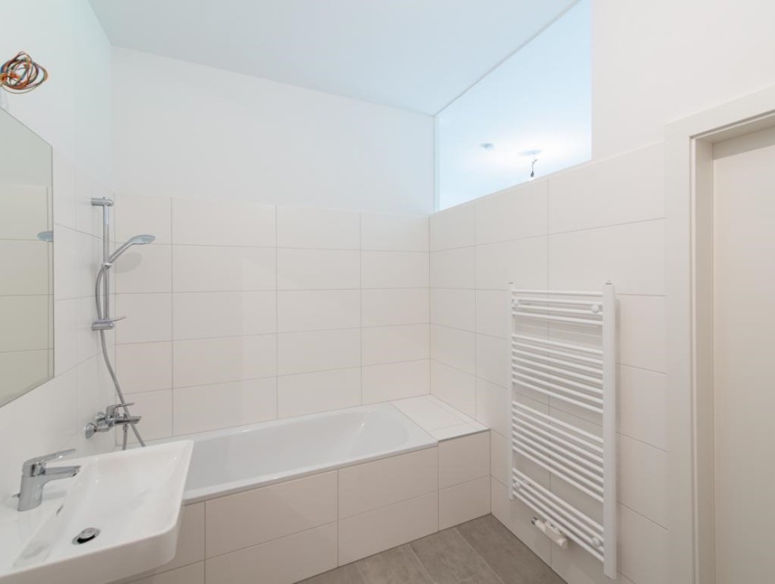 Geräumiges Badezimmer mit Duschwanne, Waschbecken, Handtuchwärmer und Waschmaschinenanschluss